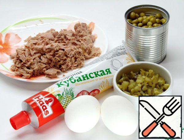 Everything is very simple. Drain the juice from the tuna can. Cut tuna, eggs and pickled cucumber into small cubes. Add two tablespoons of green peas.
