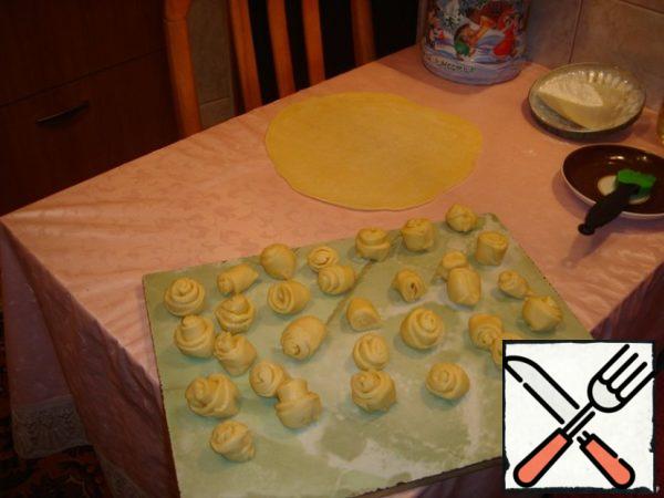 Roll out the dough into a large circle = 2 mm thick, brush with vegetable oil and roll into a roll.
Cut into pieces and mold the "roses".
Transfer the onion and chicken to a large saucepan by volume, put the sliced potatoes on top, and then the "roses" from the dough.