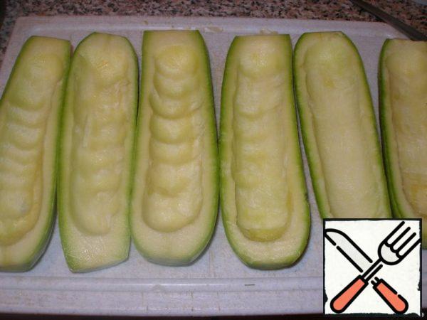 Prepare the zucchini: wash, cut lengthwise, carefully remove the pulp with a teaspoon (without damaging the edges and bottom).
