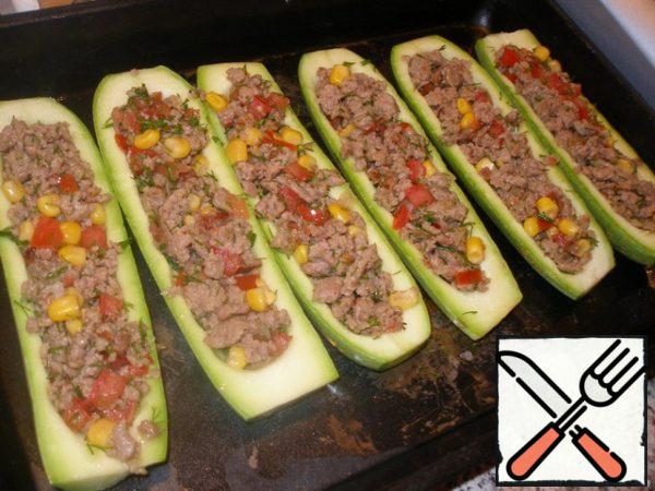 Mix the finished minced meat with vegetables and pour this mixture over the prepared zucchini.
