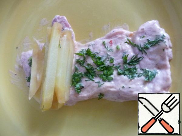 Finely chop the greens. Plate pork sprinkle with herbs, put 9-10 bars of potatoes on one side, turn and fasten with a toothpick.