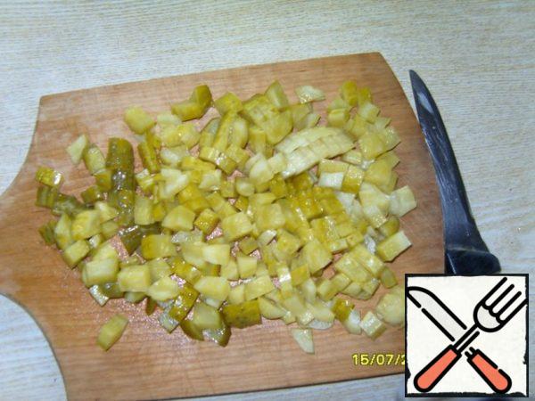 Cut the pickled cucumbers and also put them with the peas and onions.
