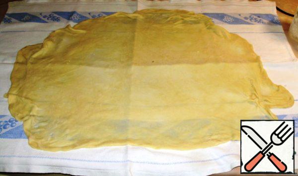 Roll out the strudel dough on a floured towel and knead it with your hands.

