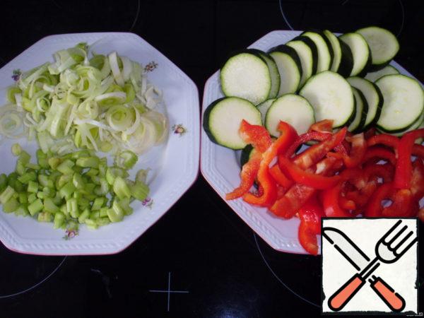 Cut vegetables: zucchini - slices, pepper - slices, leek - rings, celery stalks - slices.
