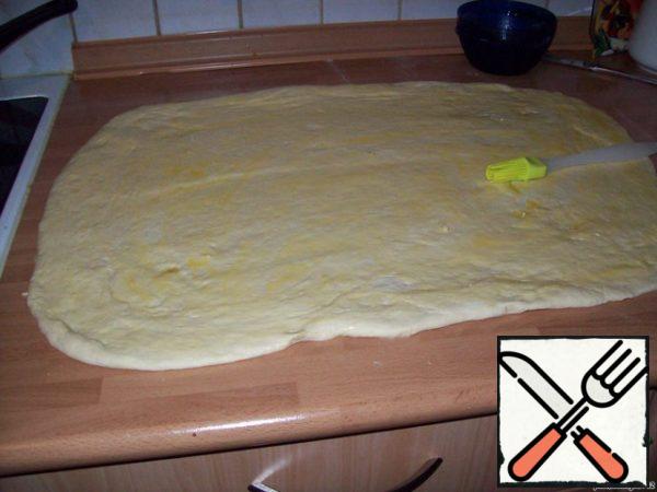 And roll out into a layer about 1 cm thick. Don't roll out too thin.
The layer is lubricated with melted margarine or butter, turn into a roll and cut into pieces 5 cm.