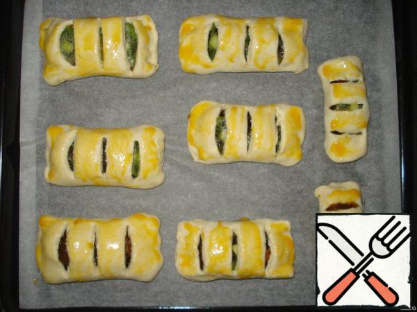 Place the puff strudels on a baking sheet covered with parchment paper in advance. Brush them with yolk on top. Preheat the oven to 220 degrees (about 5 minutes). Place a baking tray with strudels in the oven and bake for about 15-20 minutes, until the strudels turn golden.