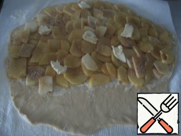 Grease the dough with butter and sprinkle with breadcrumbs, leaving a 10 cm wide strip from the edge. Distribute the apples evenly, mix the cinnamon with sugar and sprinkle the apples. Put a few pieces of butter on the apples. Roll up the roll with a towel.
