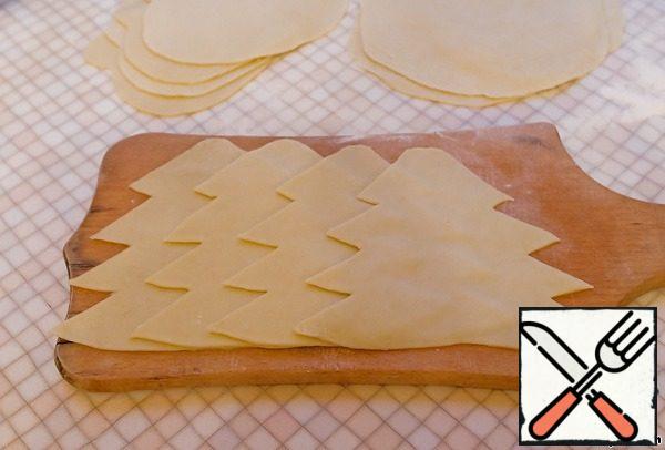 Roll out the finished dough into a thin layer. Cut the cakes in the shape of Christmas trees. You can just roll out thin cakes.
