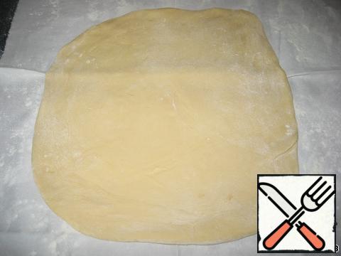 Then cover the dough with something and leave to rest for 30 minutes.
On the table, spread out a clean cloth or napkin, sprinkle it well with flour. The dough is first rolled out, turning from one side to the other and sprinkling the fabric with flour.