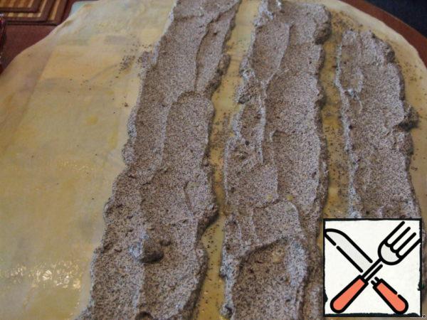 Put the dough on the table (I have a flexible dough backing on my table) and spread the filling along the long edge in three rows at a distance of 2-3 cm; grease the dough between the rows of filling and the rest of the dough with melted butter.
