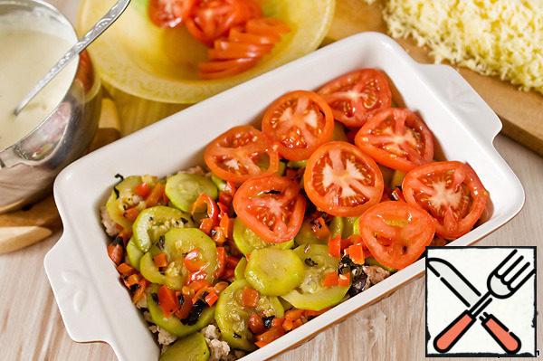 Put the minced meat in a baking dish, then the fried vegetables. Place the chopped tomatoes on top.
