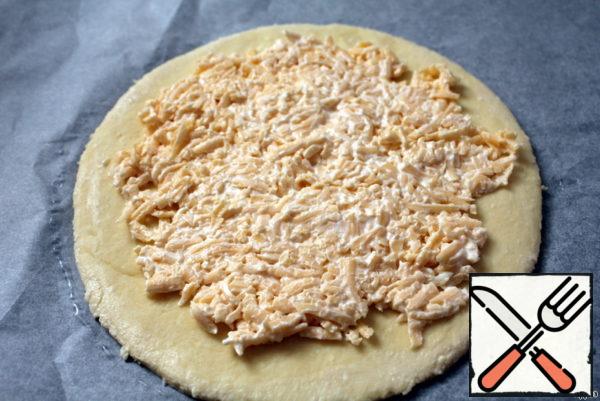 Put a smaller circle on a baking sheet covered with parchment, grease the edges with water. Distribute the filling on the surface of the circle.
