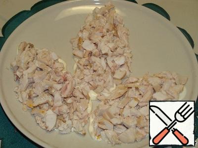 Eggs and potatoes grate on a large grater. On a plate spread a little mayonnaise in the shape of cones. Lay a chicken breast.