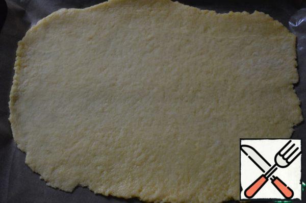 The dough is divided into two parts. Each part of the dough roll out on the surface, floured as thin as possible. Dough with a rolling pin gently shift on a baking sheet, laid parchment and greased with vegetable oil.