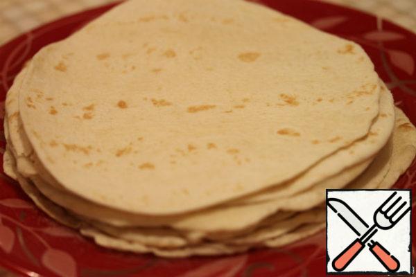 Ready tortillas folded on top of each other. Cover with a Board or any other flat load that they were flat without air tubercles which are formed from-for baking powder. But without it, they will be rubber. Cover them with a towel so they don't dry up. If you do not use immediately, be sure to put them in the package. In the refrigerator can be stored for a few days and in the freezer for a couple of months. If they do dry up and break down, heat in the microwave before use.