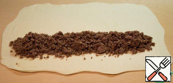 Roll out the puff pastry in a thin layer.
Lay the minced meat along the dough, leaving 7-8 cm from the edge.
