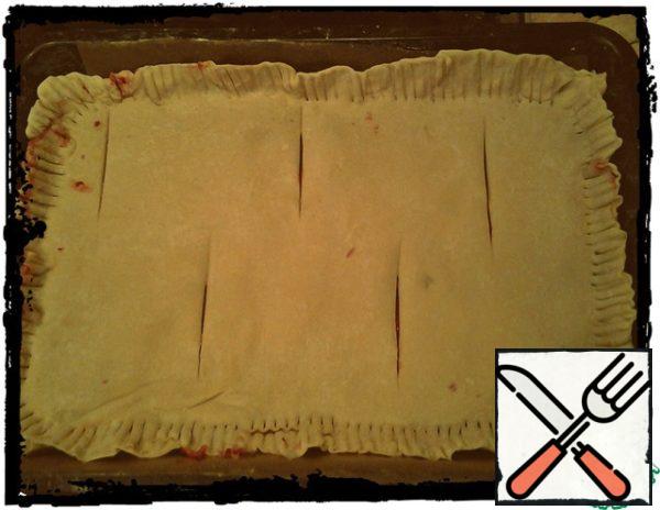 Roll out the second layer, lay it on the first one, fastening it at the edges. Then press the edges with a fork, and in the middle of the strudel make transverse incisions of the upper layer of dough.

