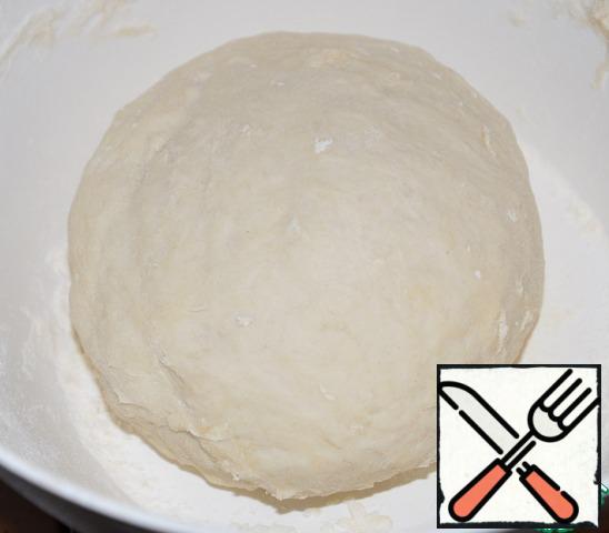 Stirring, add 2/3 Cup hot water. Kneading dough. It should get soft and not sticky. Cover the bowl with the dough and leave for 20 minutes.