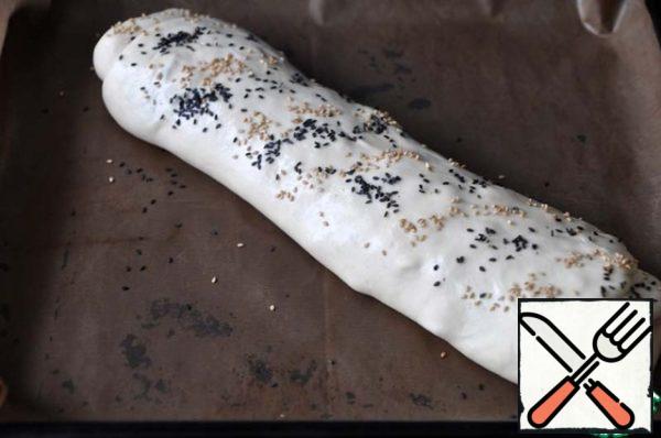 Put the roll seam down on a baking sheet covered with baking paper.
Grease the roll with protein, sprinkle with sesame seeds.
Put in the oven heated to 200 degrees, bake until Golden for 30 minutes.