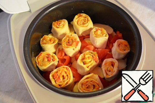 Cut the roll into pieces-rolls. And put them on top of the pepper.
Add 100 ml of water to the slow cooker. Add salt to the dish to taste.
