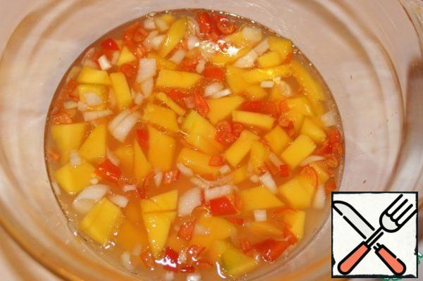 1/2 Mango peeled and cut into cubes. Shallots and chili peppers chop. Add juice and oil.