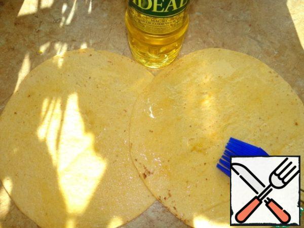 Place the tortilla on the table overlap, lubricate with oil;
