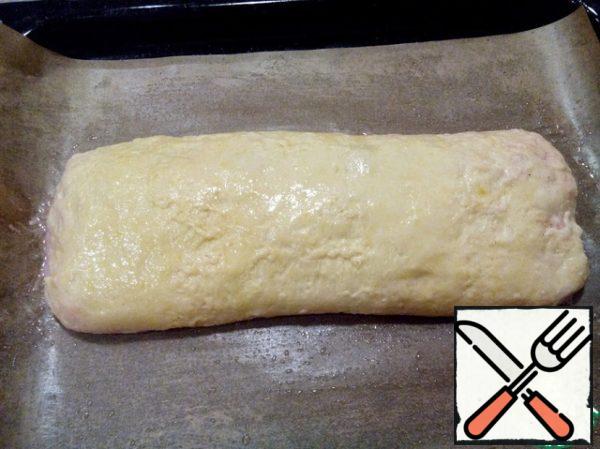 Carefully place the roll on a baking sheet, greased or lined with baking paper. Grease the top with melted butter. Put in the oven heated to 180 degrees.