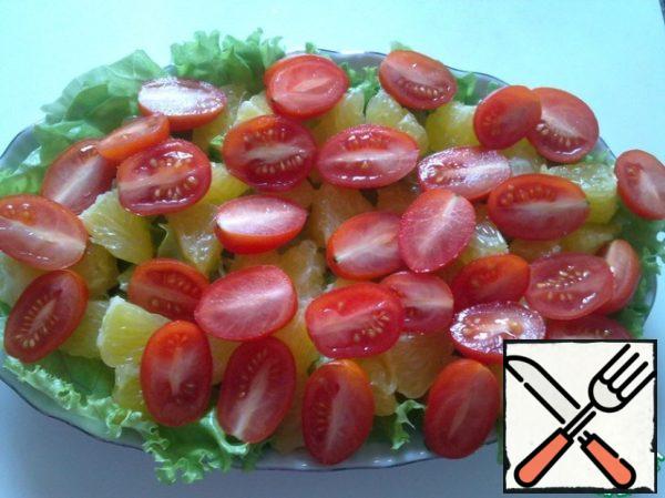 Arrange the orange slices on the leaves, then put the cherry tomatoes cut in half.
