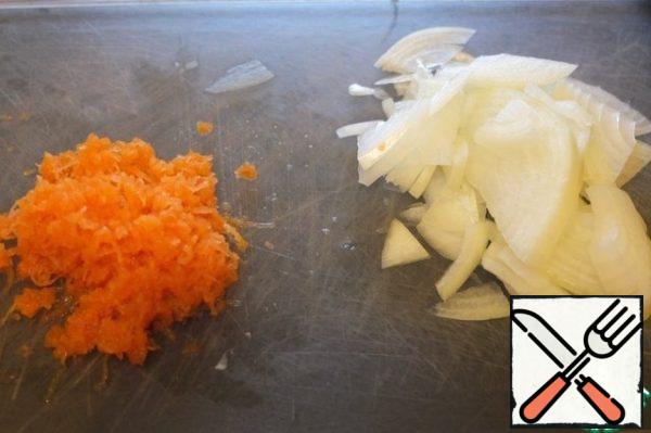 While cooking the rice, cut the onion into quarter-rings, carrot grate on a fine grater.