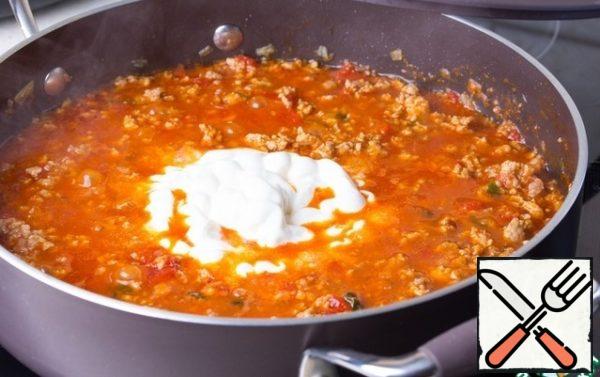 Add 50 ml of sour cream, stir thoroughly. Warm. Transfer the meat filling into a sieve or colander and let the sauce drain into a separate container.