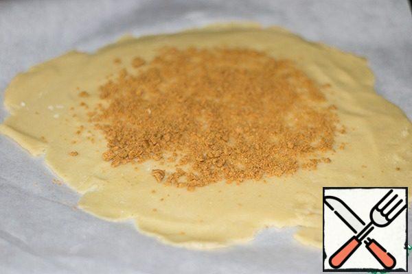 Heat oven to 180 degrees.Lay a sheet of baking paper on the table. On paper, roll out the dough to 5 mm thick. Transfer the paper with the dough on a baking sheet.Cookies finely crumble and put on the dough.
