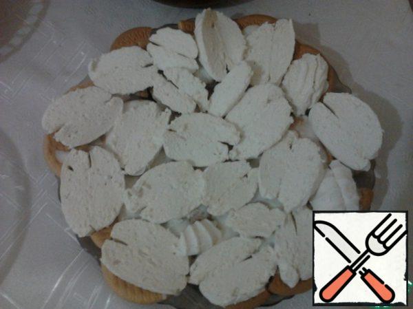 Marshmallow cut as thin as possible on the plate and put a layer on the cookie. Grease with sour cream.