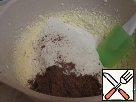 Then pour the sifted flour, baking soda, cocoa powder, vanilla sugar, mix with a spatula.