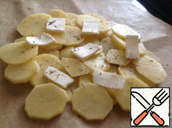 Stepping back from the edge by 5 cm, lay out layers of potatoes, salt, pepper, rosemary and butter.
