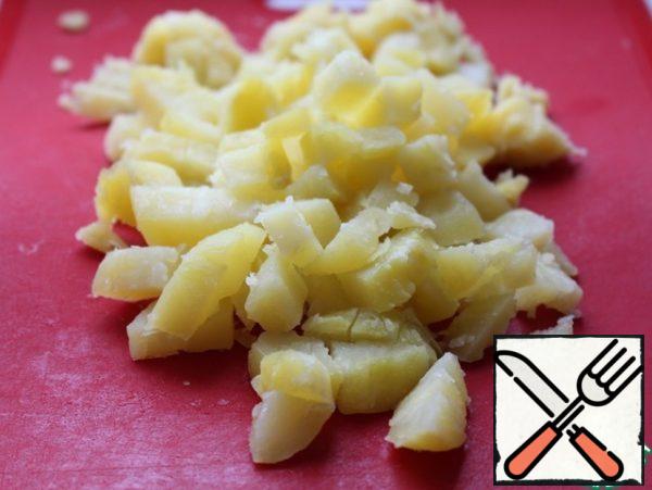 Boil potatoes in their skins, peel and cut into cubes.