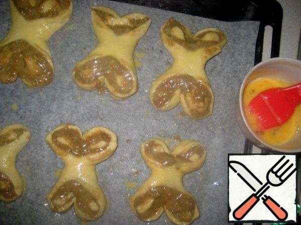 Place the "butterflies" on a baking sheet covered with baking paper and leave for 15 minutes.
Start preheating the oven to 180 degrees.
After 15 minutes, grease the buns with beaten egg and send them to bake in a preheated oven for 15-20 minutes.
Take out the buns and let them cool.
