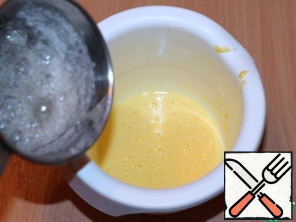 Without turning off the mixer, pour a thin stream of sugar syrup into the yolks, continue to whisk until completely cooled. The mass should become thicker.