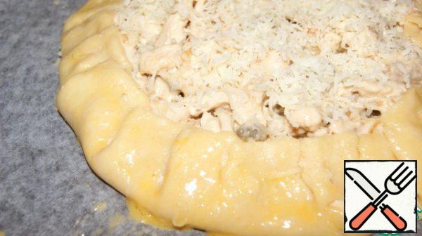 Place the dough on a baking sheet.
Retreat from the edge of 3 cm, place the filling in the center. Throw the edges of the dough on the filling, making tongs. Grease the dough with egg and sprinkle the whole galette with cheese, including the dough.