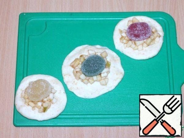 Beat the risen dough. It is divided into 16 parts. Roll out each part of the dough into a circle, put the filling of apples and 1 marmalade.
