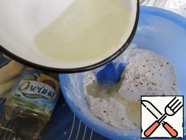 When the water with oil boils, pour into the flour mixture. And immediately begin to knead the custard dough. First using a spatula until the dough is hot.