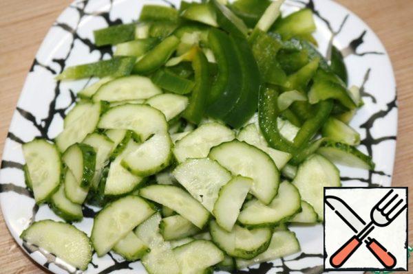 Next, we will deal with our vegetables. All cut the cucumber in half rings, pepper strips.