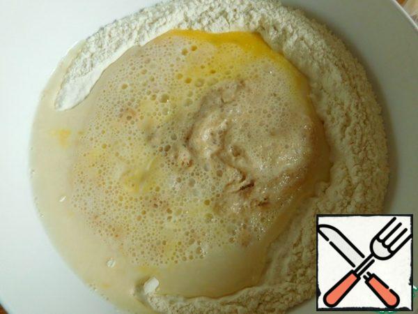 In the flour mixture, make a deepening and pour the yeast mixture and beaten egg.