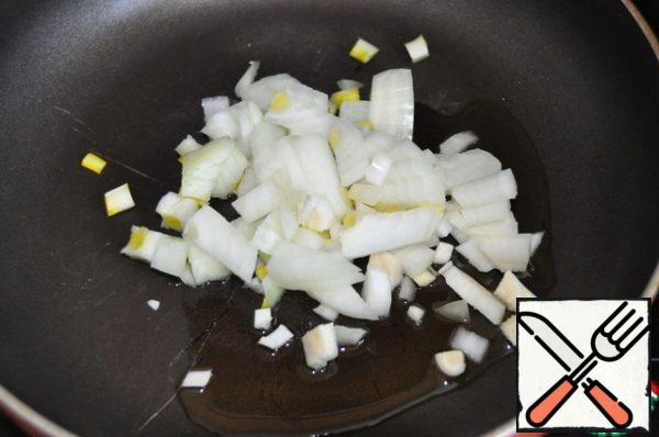 While the dough is rising, we will prepare the filling. Onions clean and cut into small cubes. On a hot pan pour vegetable oil and fry the onion for 2 minutes until transparent.