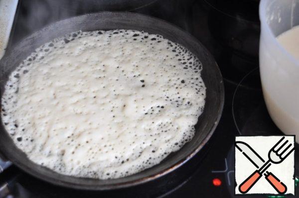 Grease a preheated frying pan (preferably pancake pan) with oil, pour the dough with a ladle, spread it over the surface of the pan. Bake over medium heat (I have 4-5 out of 6). As soon as the dough changes color, flip the pancake.
Bake for about a minute on the reverse side. Transfer the finished pancake to a plate.
When baking, periodically lubricate the baking sheet with oil.
