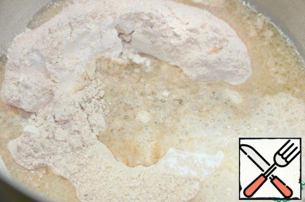 In a glass, mix olive oil and hot water. Pour the liquid into the dry ingredients and knead the dough with your hands.
