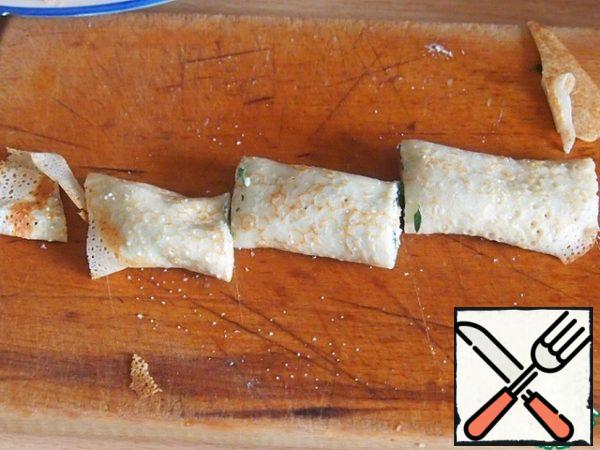 Twist the pancake roll, cut off the rounded edges from the sides. Cut the pancake into three parts.