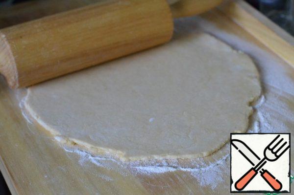 Sprinkle the cutting Board with flour.
The cooled dough is rolled into a circle with a diameter of 30cm.