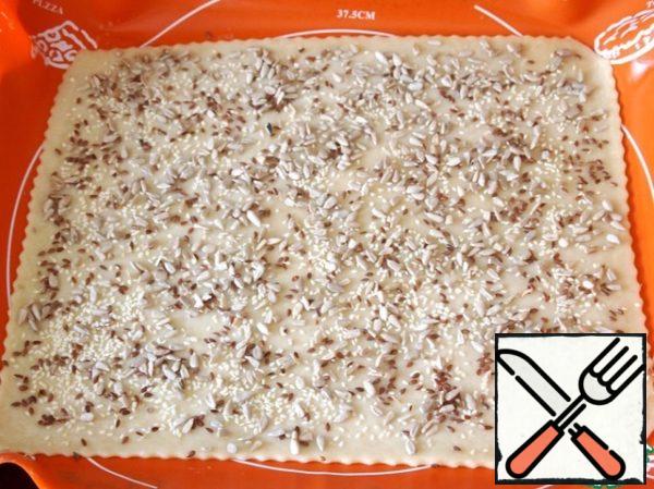 Sprinkle with flax seeds, sesame seeds and sunflower seeds. To laminate the top with a rolling pin, so that the seeds are kept a tighter hold.