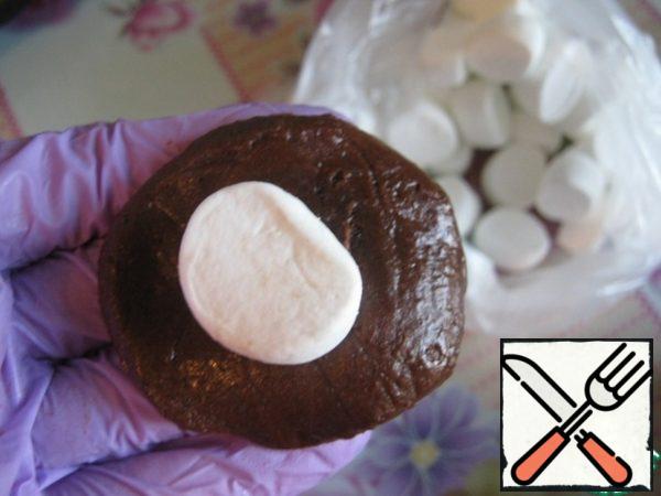 Take a small amount of dough (about 25 -30 g), roll the ball, make a cake, put marshmallow in the middle, pinch and roll the ball. The dough is a little sticky, so periodically moisten with water hands.