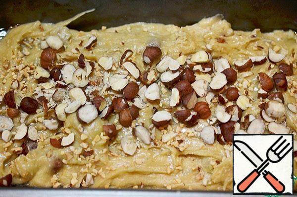 Grease the baking dish with oil and lay out the dough. Sprinkle with coarsely chopped nuts on top.
